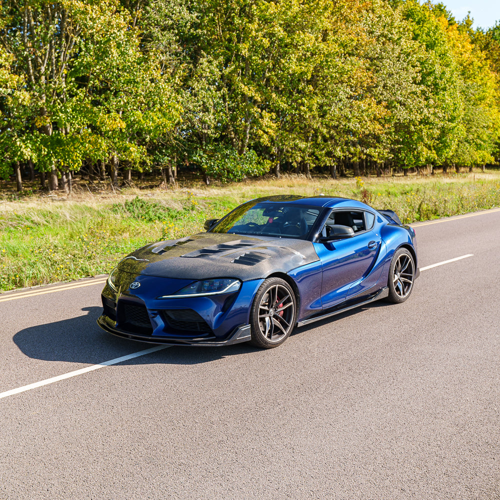 Carbon fiber side skirts for Toyota Supra 2019+ A90 by CT Carbon, showcasing sleek, aerodynamic design on the car's side.
