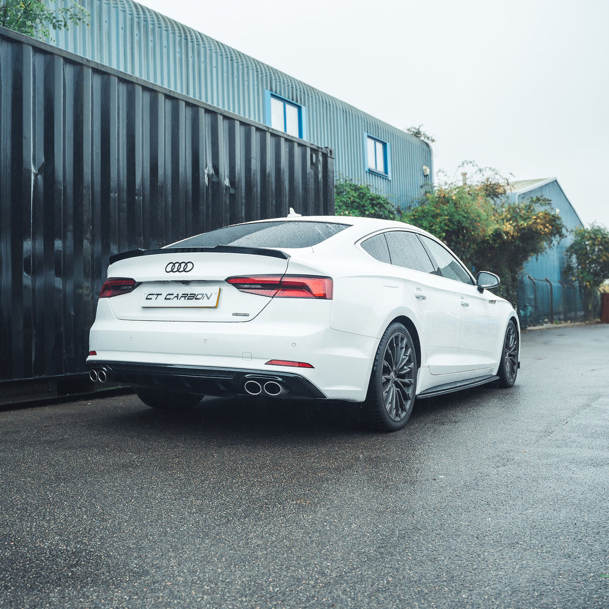 Carbon fiber gloss black diffuser for Audi A5/S5 B9 2016-2019 by CT Carbon, shown installed on the vehicle's rear bumper.