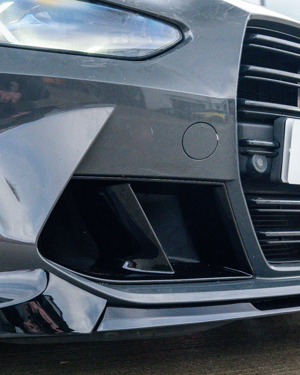 Black carbon fiber air ducts for BMW G80/G81 M3 and G82/G83 M4 from CT Carbon, showing close-up of gloss black finish and aerodynamic design.