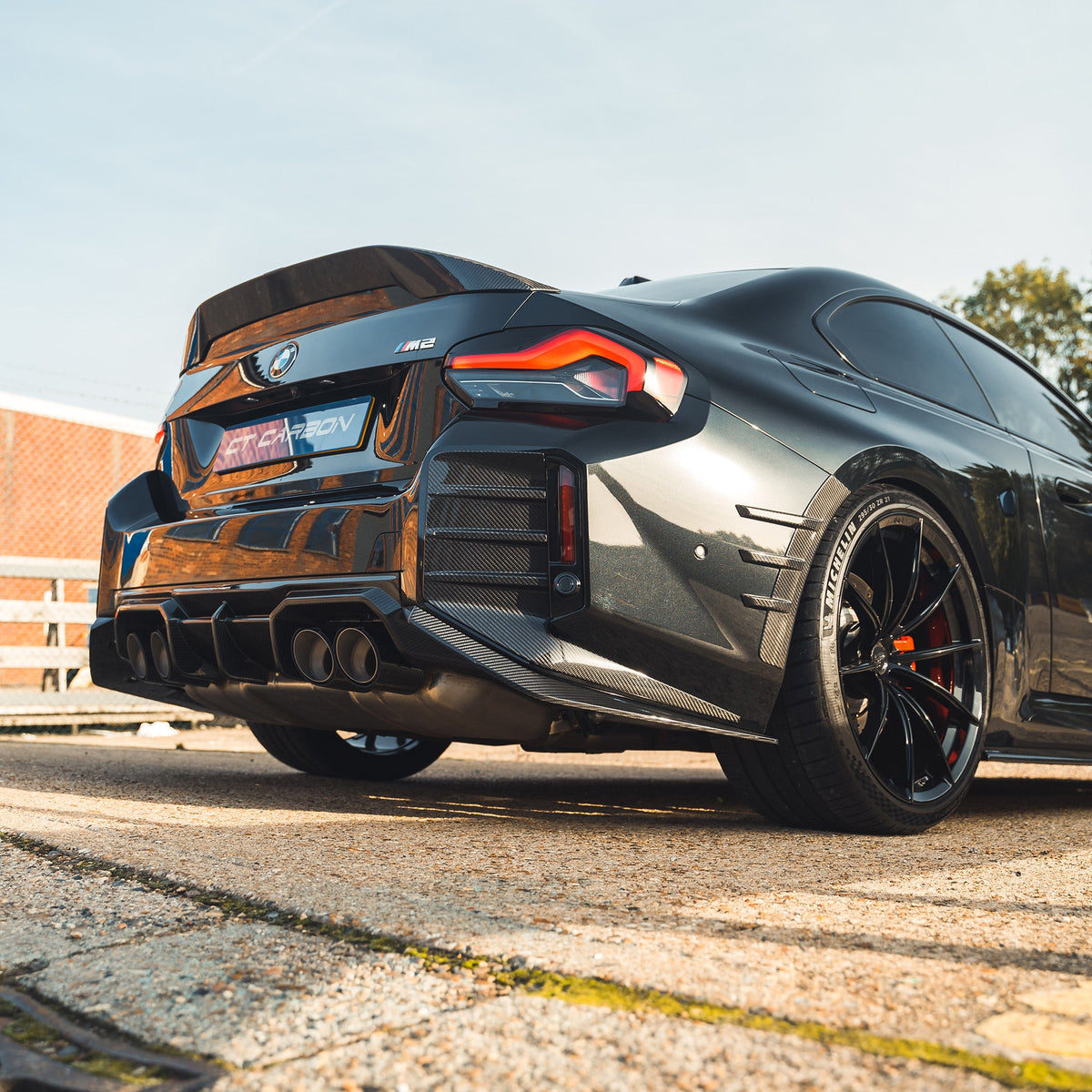 BMW G87 M2 carbon fibre rear bumper corners accessory by CT Design, showing sleek, lightweight carbon fiber detail on the vehicle.