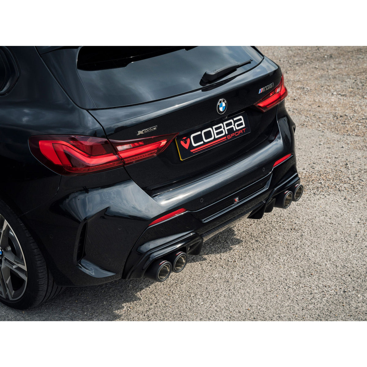 Cobra Sport BMW M135i F40 quad exit M3 style cat back performance exhaust installed on black car.
