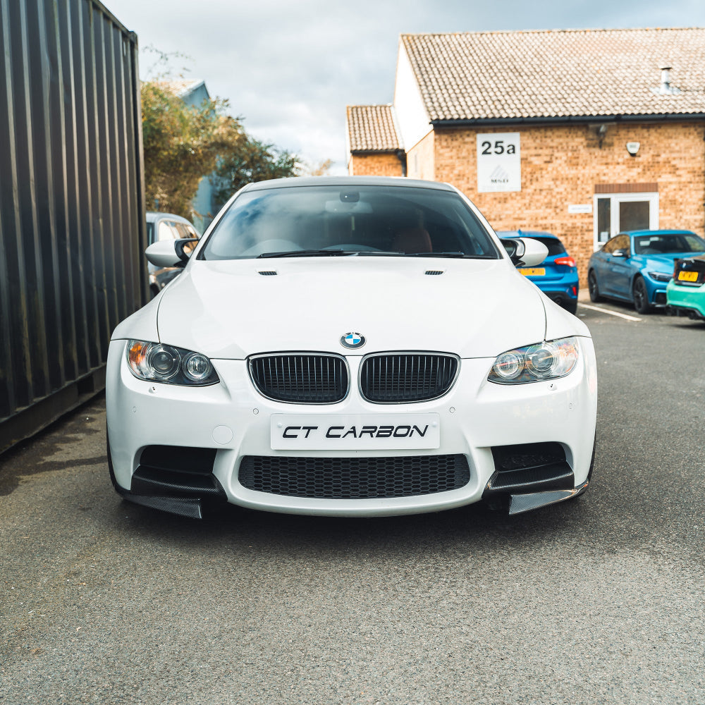 BMW M3 E92/E90 carbon front canard splitters by CT Carbon, showcasing aerodynamic components on the car's front bumper.