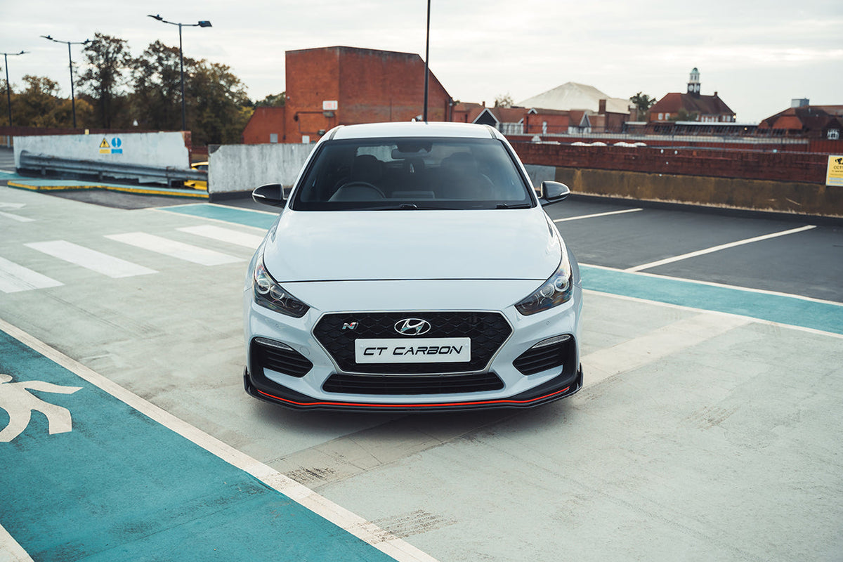 Hyundai i30N front carbon fiber splitter by CT Design, pre-facelift model, showing sleek aerodynamic design and textured carbon finish.