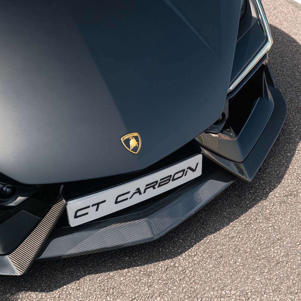 Lamborghini Revueltó carbon fiber front splitter by CT Carbon, with intricate aerodynamic design and sleek black finish.