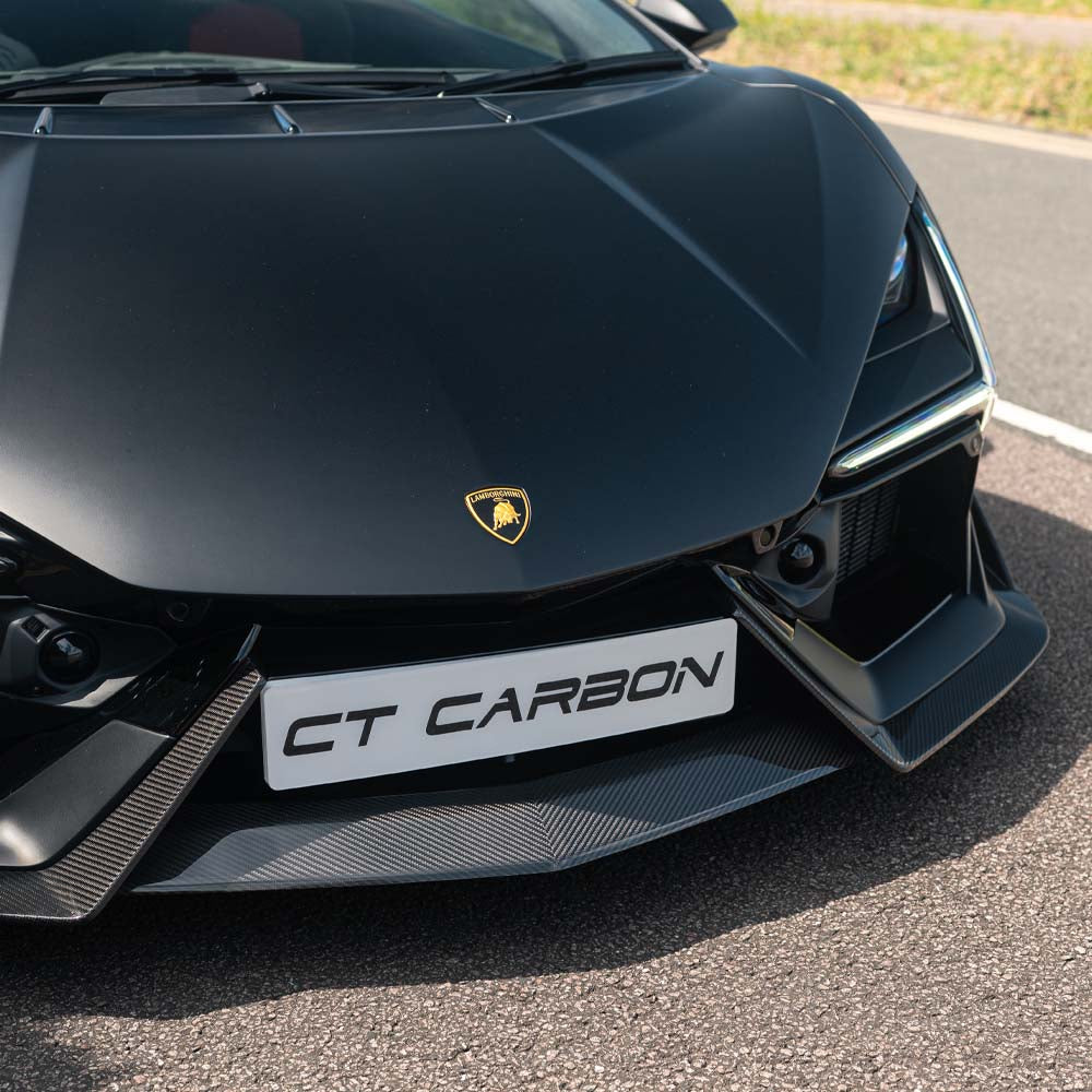 Carbon fiber Lamborghini Revetto front splitter by CT Carbon, showcasing sleek aerodynamic design on a high-performance car.