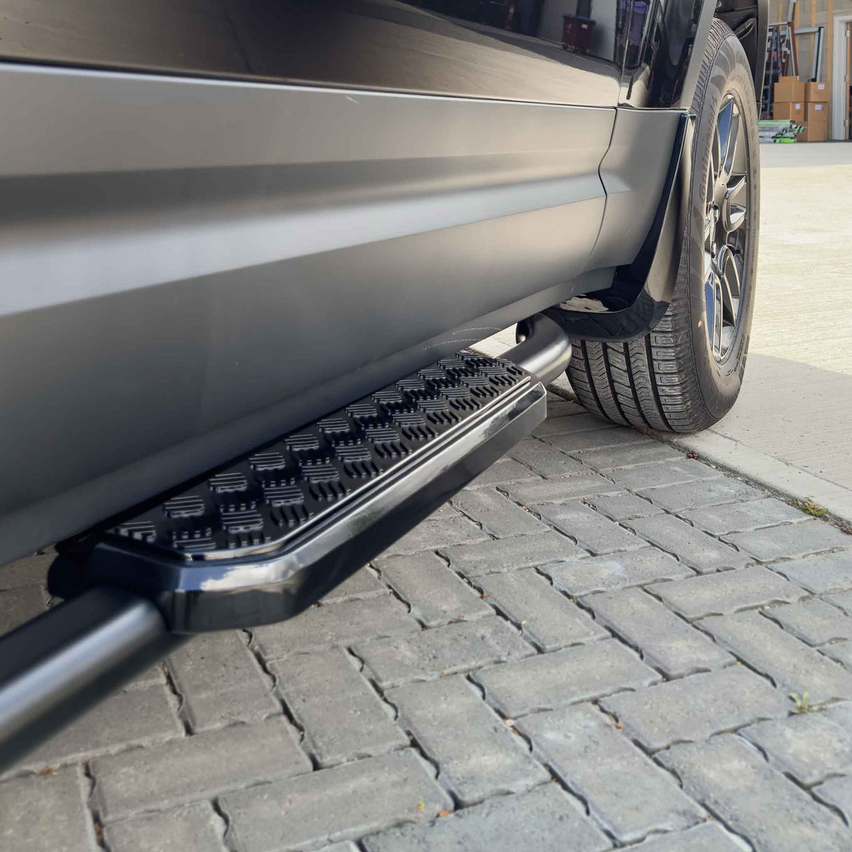 Land Rover Defender L663 90 side steps by CT Carbon, sleek black accessories mounted alongside the vehicle for easy access.