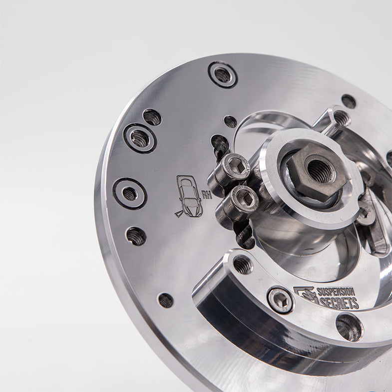 Suspension Secrets adjustable camber and caster plates for BMW F87 M2 Competition, showing black metal suspension linkages.