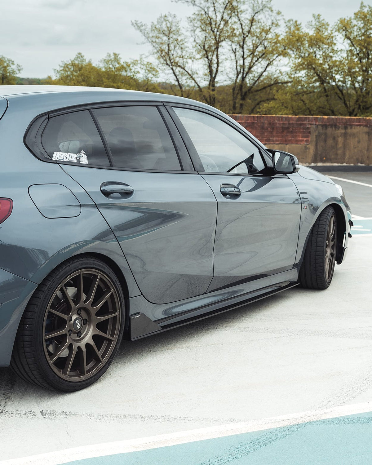 BMW 1 Series F40 carbon fiber side skirts by CT Design, showcasing sleek, textured carbon fiber surface on the side of the car.