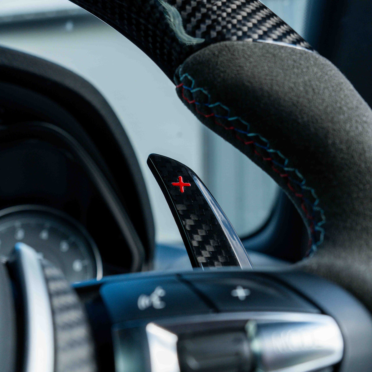 BMW carbon fiber magnetic shifter paddles by CT Carbon installed on a car steering wheel.