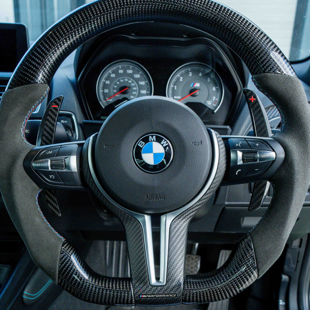 BMW carbon fiber magnetic shifter paddles installed on steering wheel, accessory by CT Carbon, featuring a sleek, lightweight design