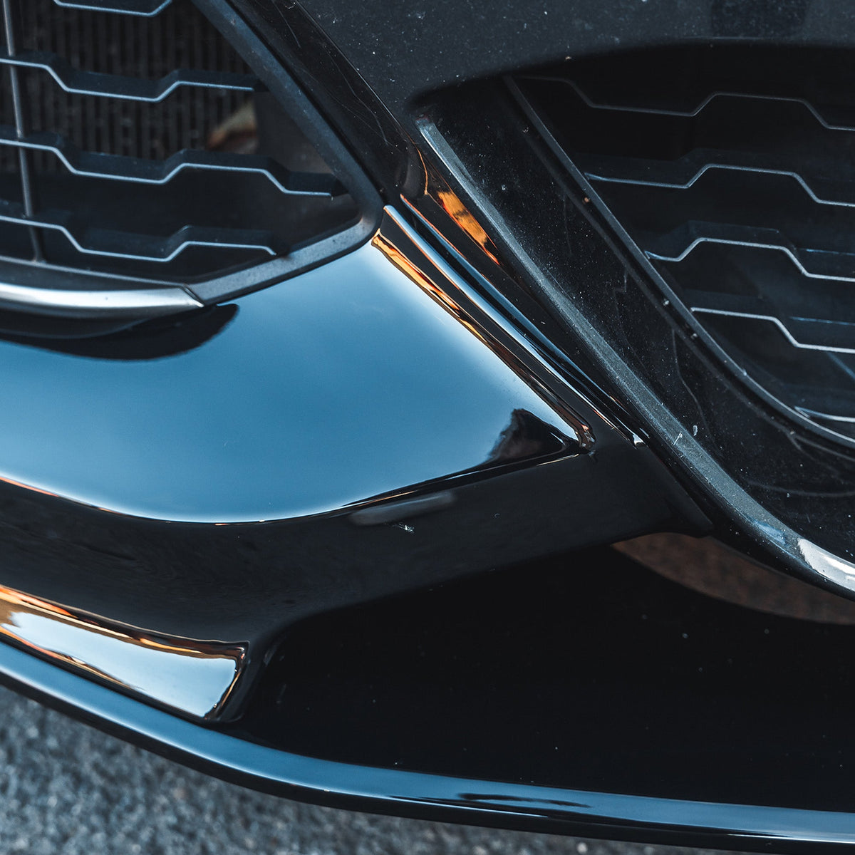 BMW F20/F21 1 Series LCI gloss black splitter by CT Carbon, shown installed on the front bumper with a sleek, aerodynamic design.