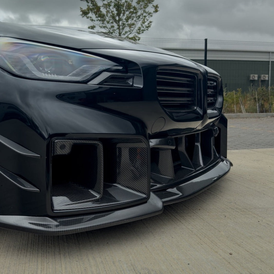 BMW G87 M2 carbon fiber front headlight add-on accessory by CT Carbon, featuring sleek carbon fiber detailing and precision fit.