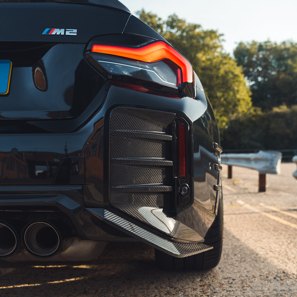 BMW G87 M2 carbon fibre rear bumper corners by CT Design, close-up of sleek, lightweight car accessory with carbon fiber finish.
