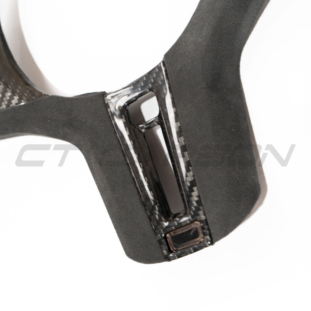 BMW Gxx M carbon fibre steering wheel trim with heating and accessories from CT Carbon, showcasing sleek, textured carbon finish.