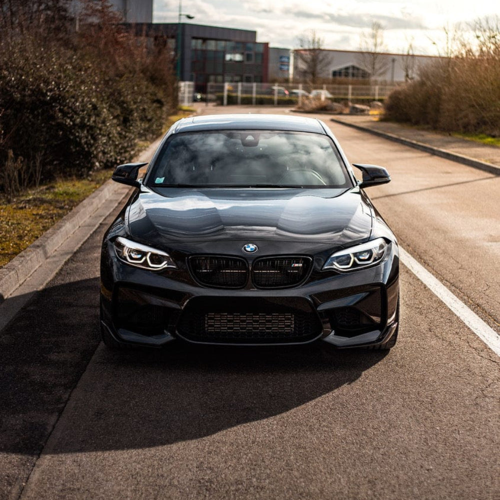 BMW M2/M2C F87 carbon fiber splitter by CT Carbon, V1 style, shown installed on the front of the sports car.