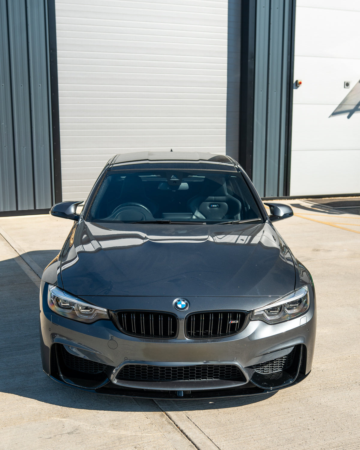BMW M3 M4 F80 F82 F83 gloss black splitter by CT Carbon, front view showing sleek aerodynamic design on coupe model.