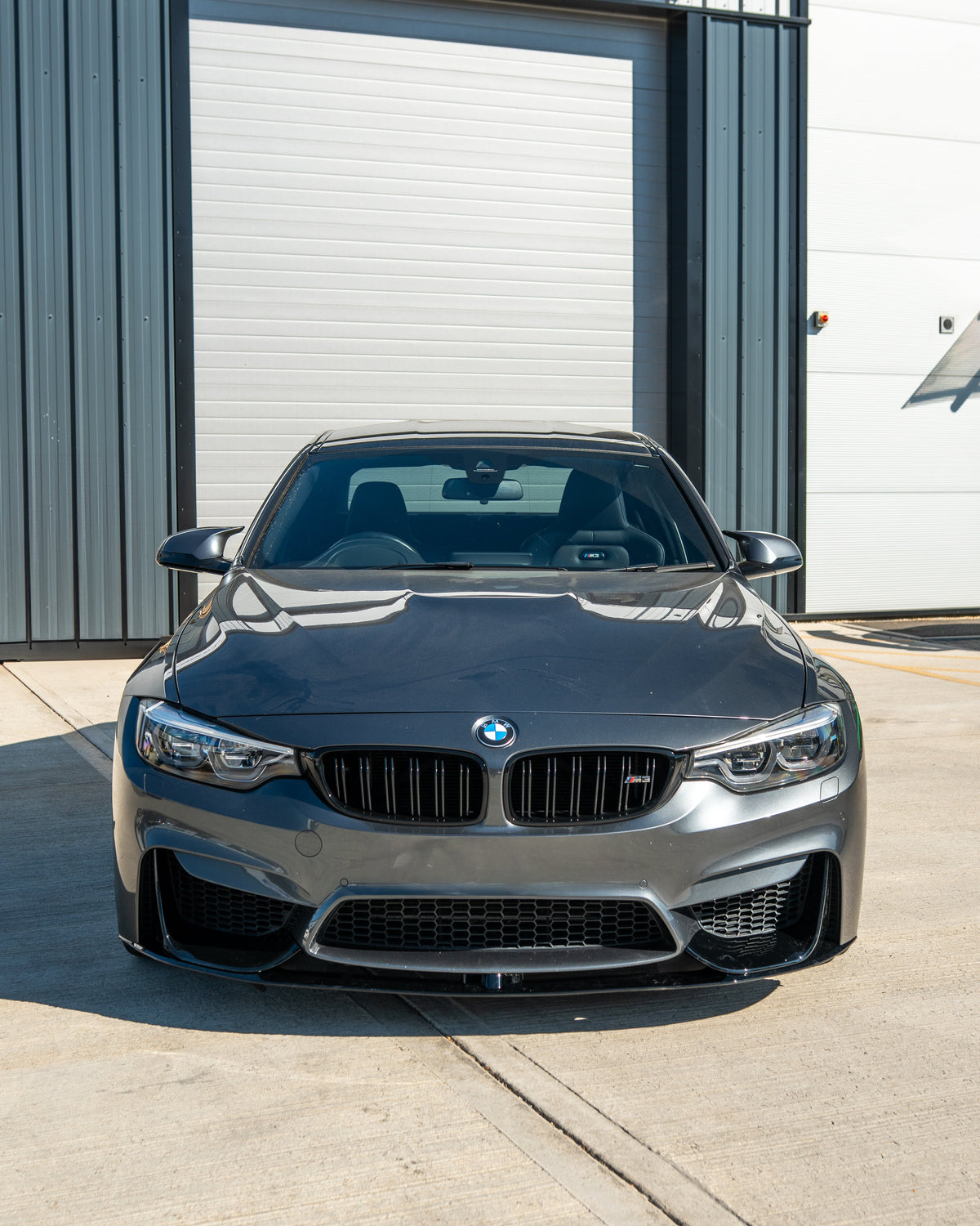 BMW M3 M4 F80 F82 F83 GLOSS BLACK splitter by CT Carbon visible on front of coupe, showcasing sleek aerodynamic design.