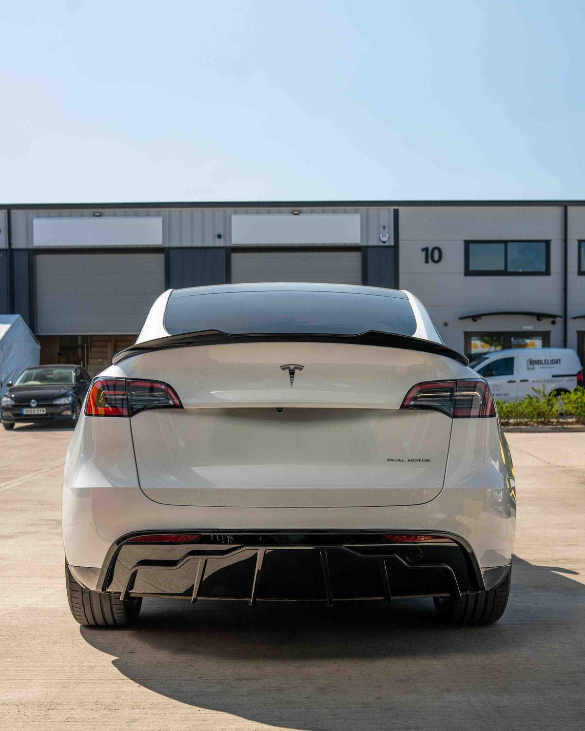 Full gloss black car kit for Tesla Model Y MK1 2020-2025 by CT Carbon, shown on a sleek vehicle with reflections.