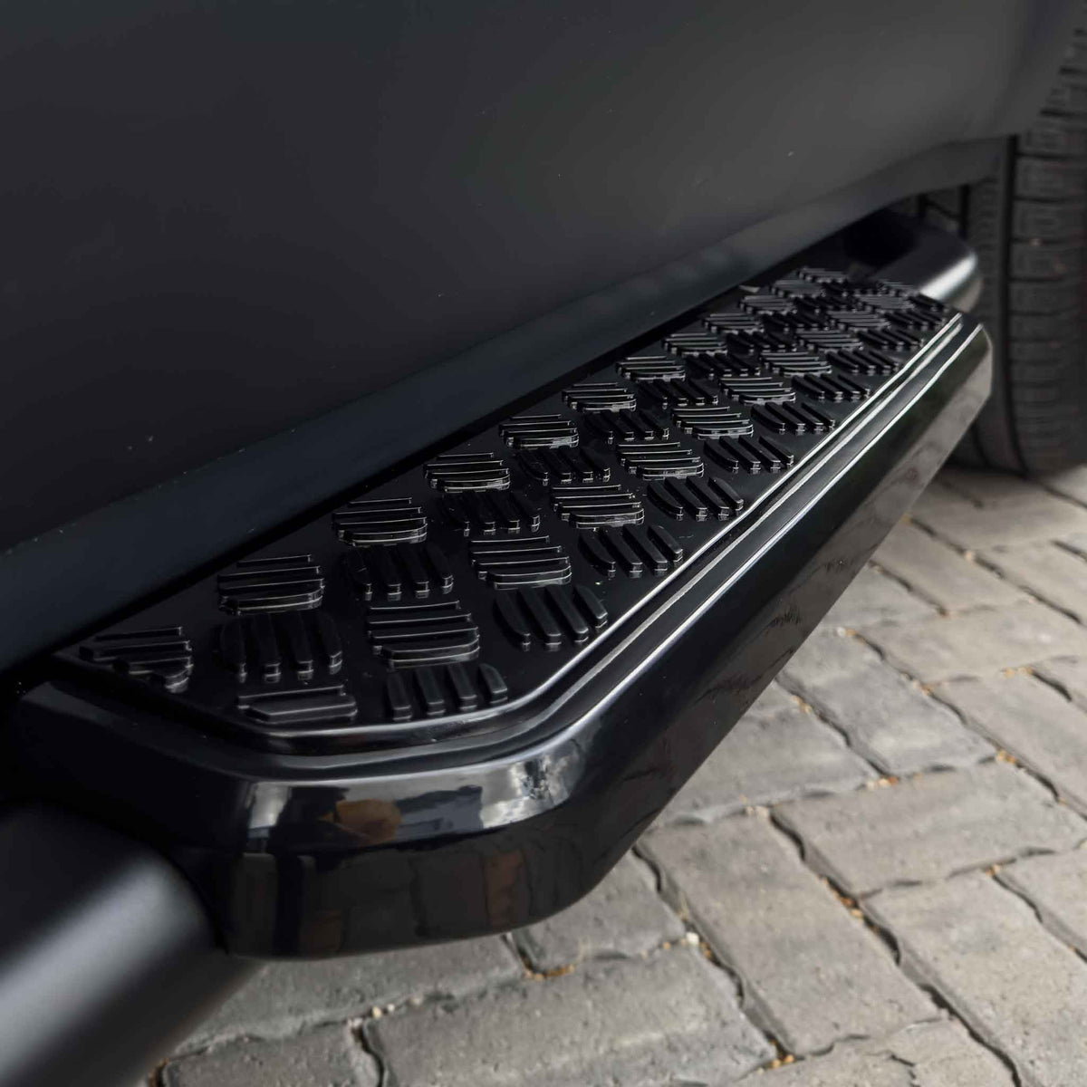 Land Rover Defender L663 90 side steps by CT Carbon, black aluminum accessories mounted along the vehicle's side for easier access.