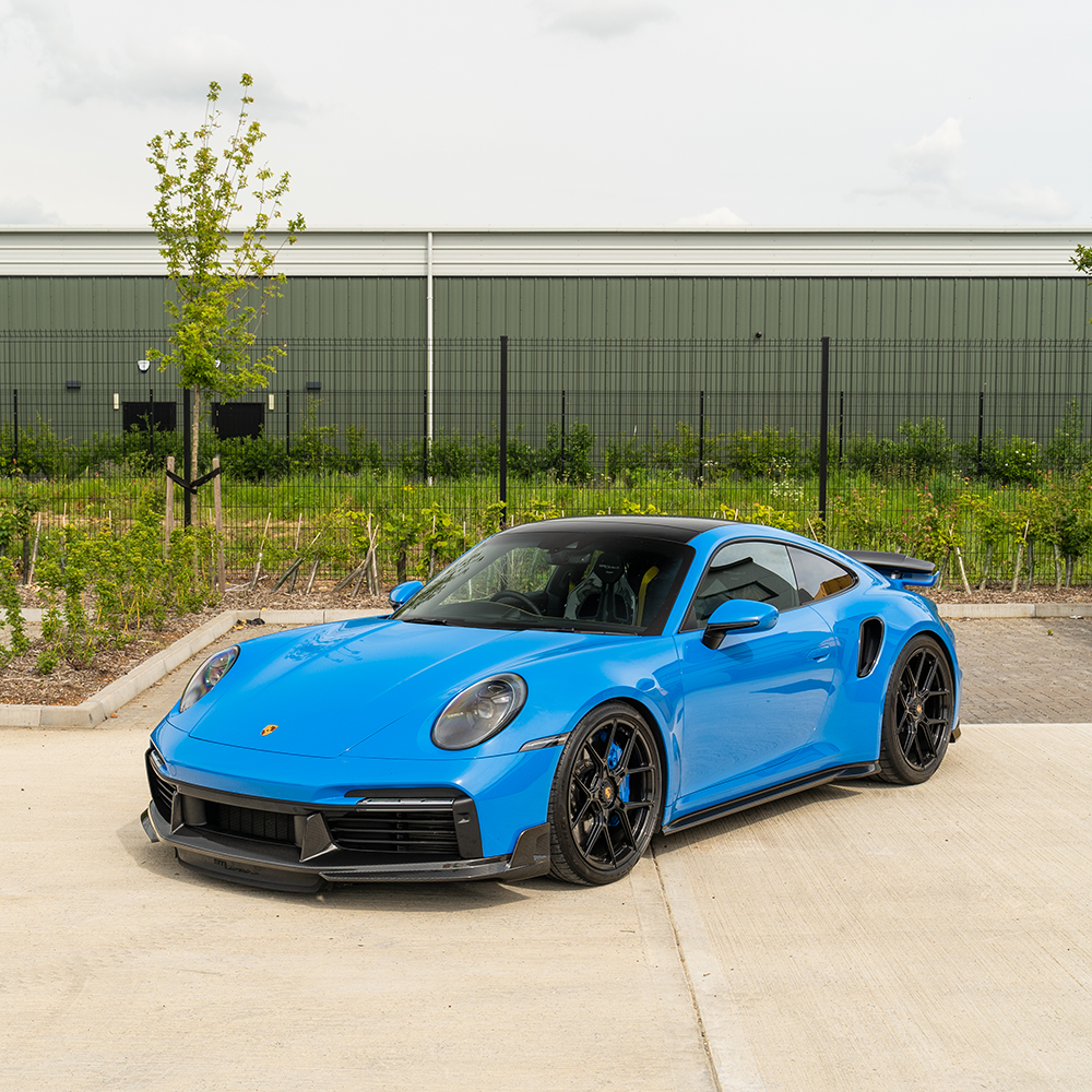 Porsche 911 (992) Turbo S carbon fiber front splitter by CT Design with side skirts, showcasing aerodynamic racing style.