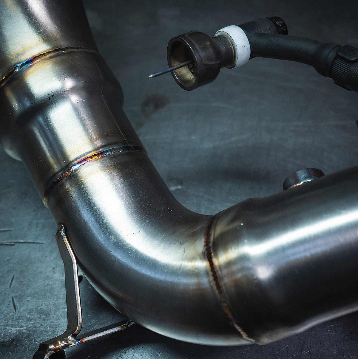 Cobra Sport VW Golf R Mk8 2.0 TSI front downpipe with sports cat, performance exhaust component, installed in a workshop setting.