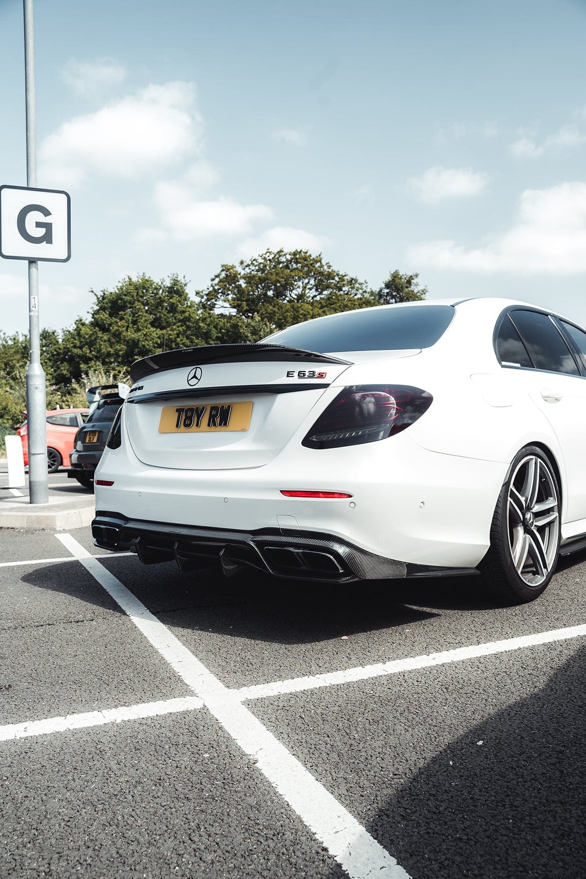 Carbon fiber diffuser for Mercedes E63 W213 2018-2020 pre-facelift by CT Carbon, showcasing sleek, textured finish on the vehicle's rear.